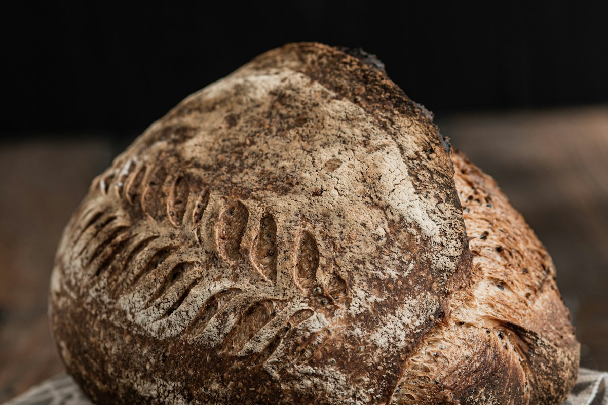 A golden, flour-dusted sourdough loaf on a wooden board